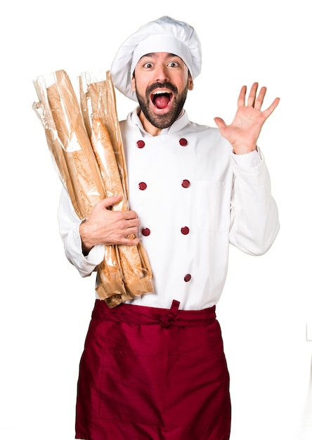 Junger Bäcker hält etwas Brot und macht Überraschungsgeste