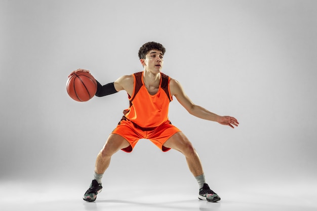 Junger Basketballspieler des Teams, das Sportbekleidungstraining trägt, das in Aktion übt, Bewegung im Lauf isoliert auf weißer Wand