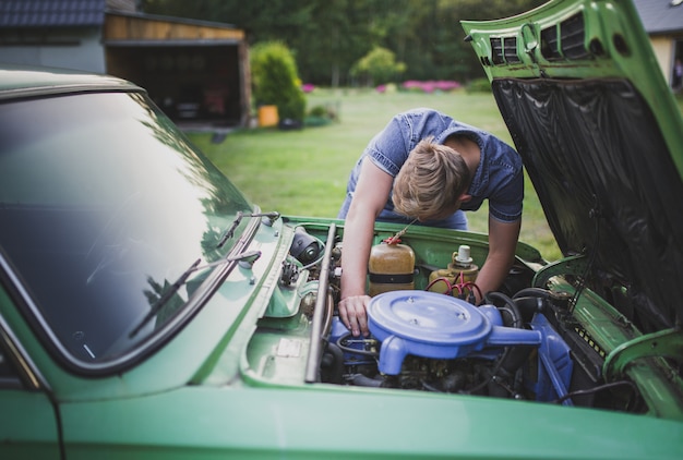 Kostenloses Foto junger blonder mann müde und enttäuscht, ein altes auto zu reparieren