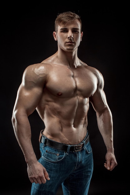 Junger Bodybuildermann auf schwarzem Hintergrund. Männlicher Oberkörper. Muskelentlastung