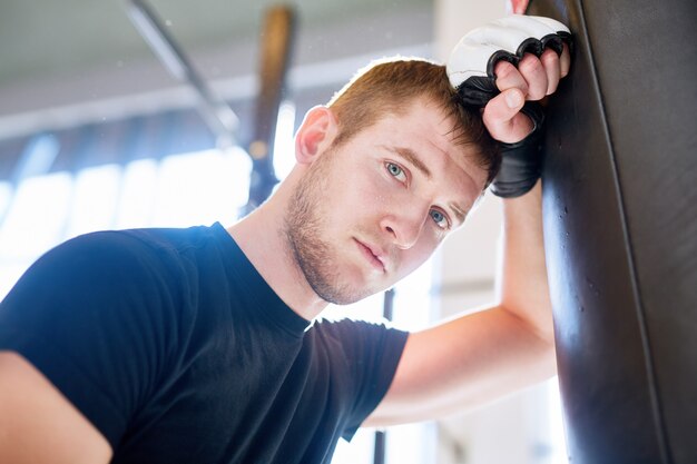 Junger Boxer, der auf Sandsack sich lehnt