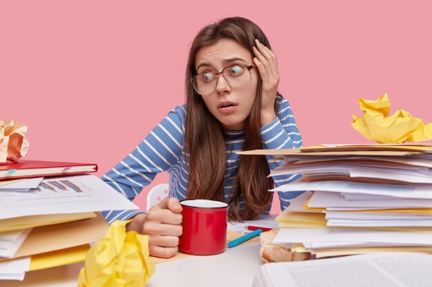 Junger brünetter Student, der am Schreibtisch mit Büchern sitzt