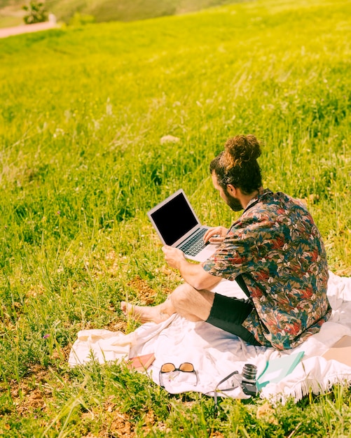 Kostenloses Foto junger brunetmann, der laptop auf natur hält