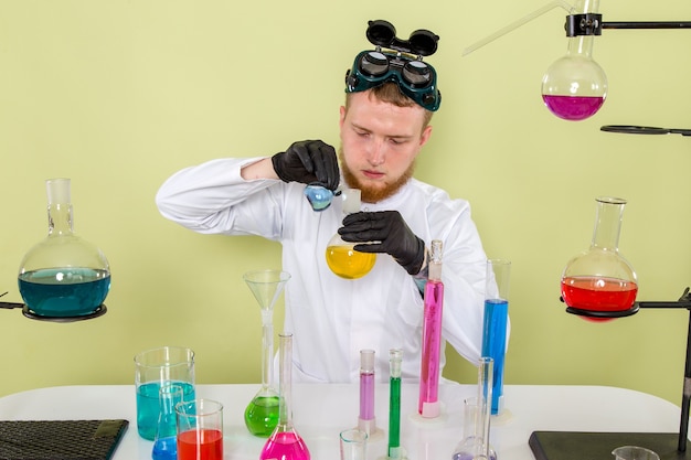 Kostenloses Foto junger chemiker der vorderansicht, der blaue und gelbe chemikalien mischt