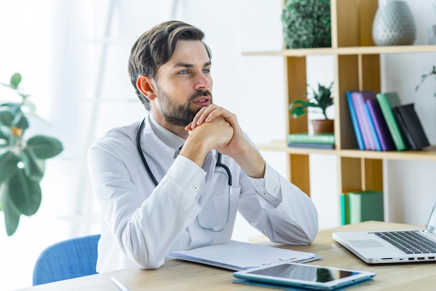 Junger Doktor, der im Büro denkt