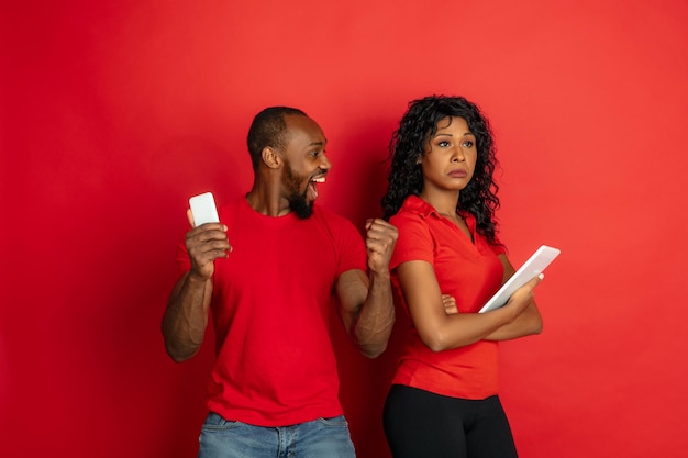 Junger emotionaler afroamerikanischer Mann und Frau auf Rot
