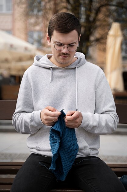 Junger Erwachsener, der draußen strickt