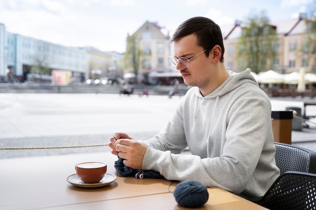 Kostenloses Foto junger erwachsener, der draußen strickt