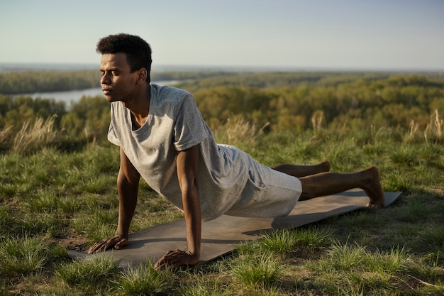 Kostenloses Foto junger erwachsener, der yoga in der natur genießt