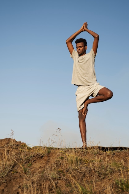 Kostenloses Foto junger erwachsener, der yoga in der natur genießt