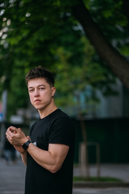 Junger erwachsener Mann in einem schwarzen T-Shirt und in Jeans geht auf einer Stadtstraße