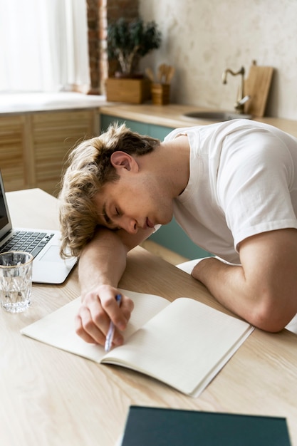 Junger Erwachsener schläft, während er Hausaufgaben macht