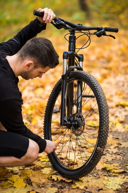 Junger Fahrer Mann Fahrer haben Problem mit niedrigem Rad im Herbstpark