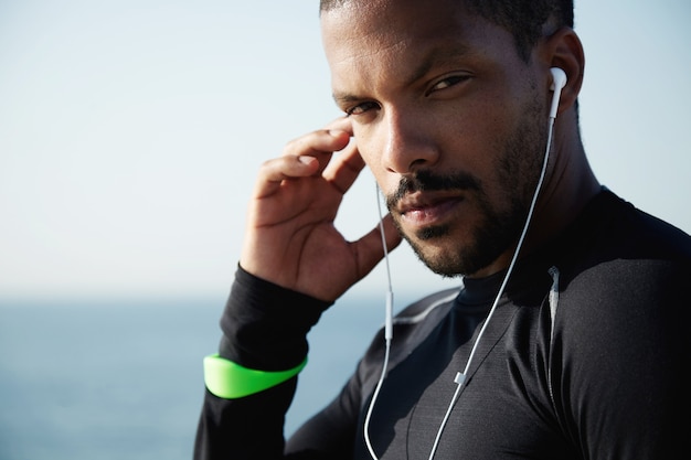 Junger fit Mann am Strand, der Musik hört