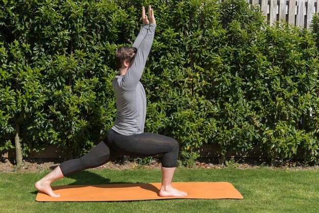 Junger fitter Mann, der Yoga praktiziert und die Stuhlpose im Freien macht