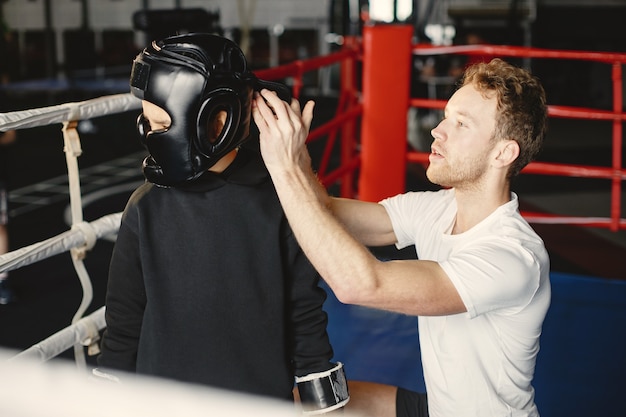 Junger fleißiger Boxer, der das Boxen lernt. Kind im Sportzentrum. Kind, das ein neues Hobby aufnimmt