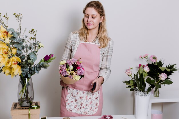 Junger Florist, der mit vereinbartem Blumenstrauß steht