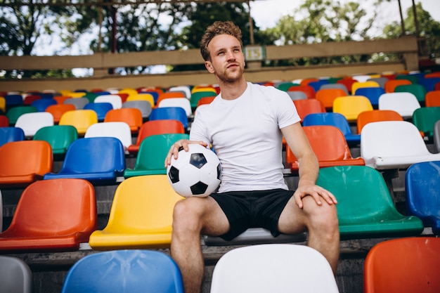 Junger Fußballspieler an den Tribünen das Spiel aufpassend