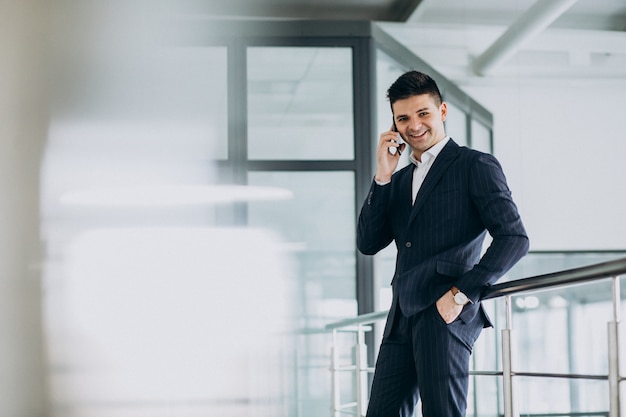 Junger Geschäftsmann, der am Telefon im Büro spricht