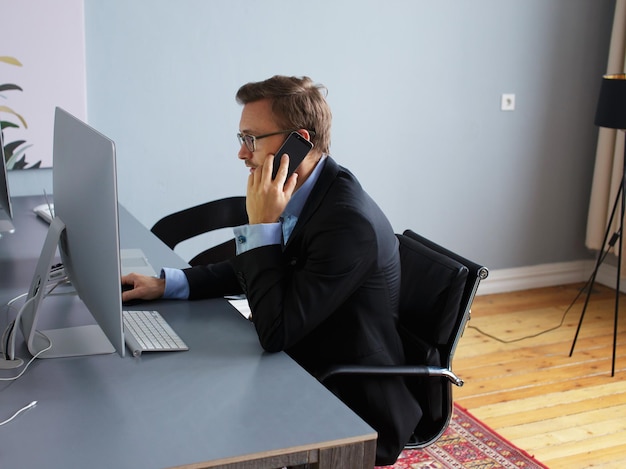 Junger Geschäftsmann, der am Telefon im Büro spricht.