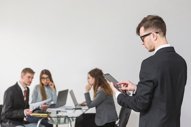 Junger Geschäftsmann, der digitale Tablette im Büro verwendet