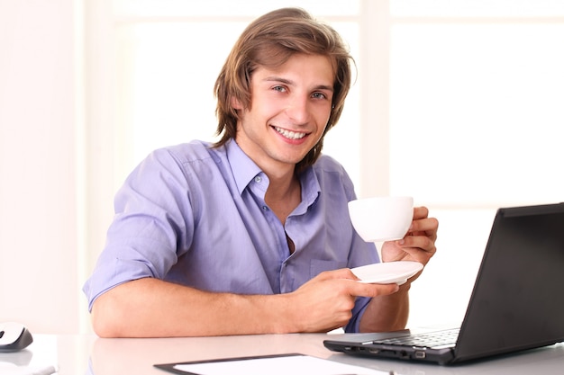 Junger Geschäftsmann, der eine Pause mit Tasse Kaffee macht