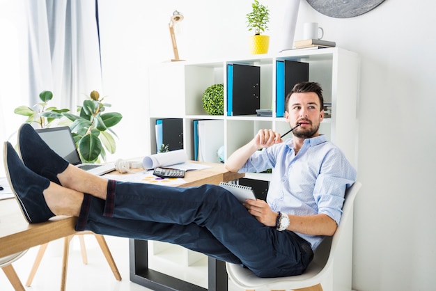 Junger Geschäftsmann, der im Büro sitzt