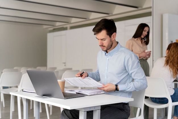 Junger Geschäftsmann, der mit Laptop an ihrem Schreibtisch arbeitet