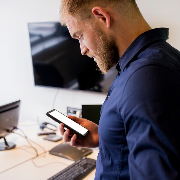 Junger Geschäftsmann, der Mobile des leeren Bildschirms betrachtet