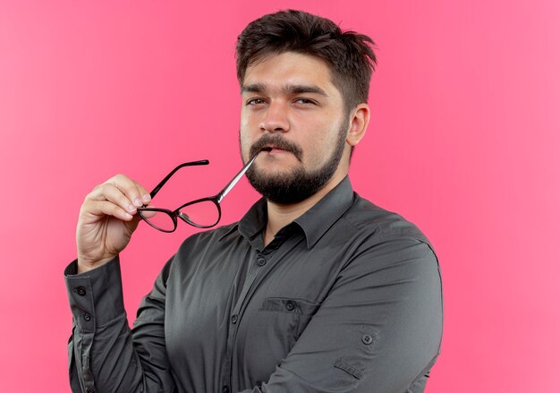 junger Geschäftsmann, der Mund mit Gläsern lokalisiert auf rosa Wand berührt
