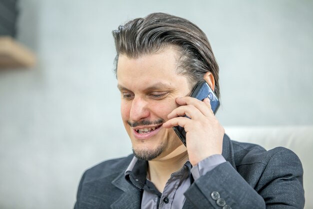 Junger Geschäftsmann, der von seinem Büro arbeitet, während er am Telefon spricht