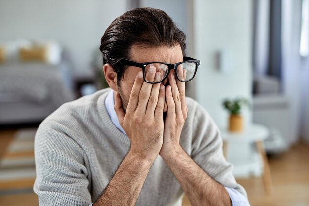 Junger Geschäftsmann fühlt sich erschöpft, während er zu Hause arbeitet