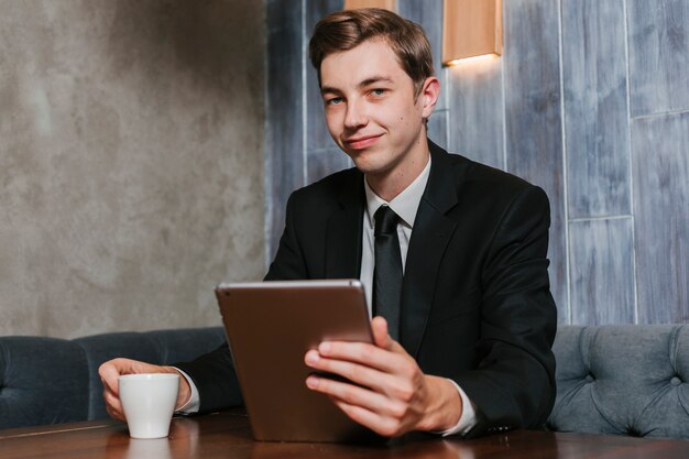 Junger Geschäftsmann im Büro, das Tablette hält