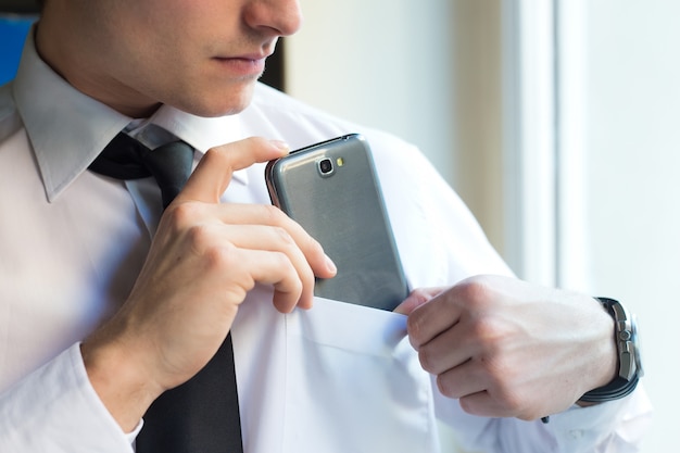 Junger Geschäftsmann mit seinem Handy im Büro.