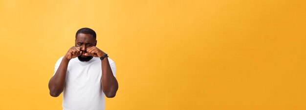 Junger gestresster mann mit der hand auf seinem gesicht, der traurigkeit und verzweiflung einzeln auf gelbem hintergrund zeigt