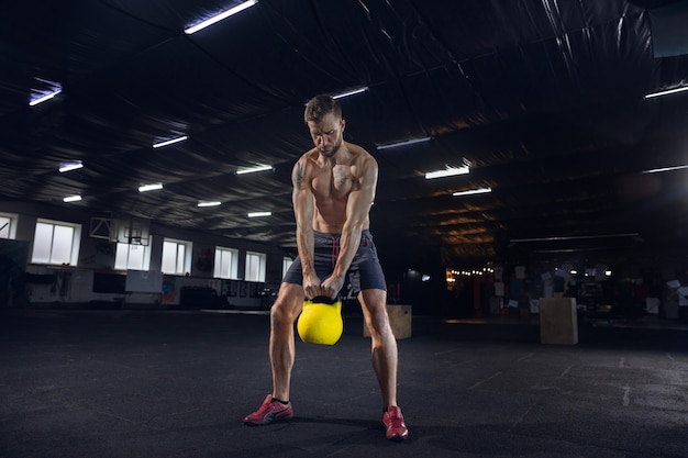 Kostenloses Foto junger gesunder männlicher athlet, der übungen im fitnessstudio macht