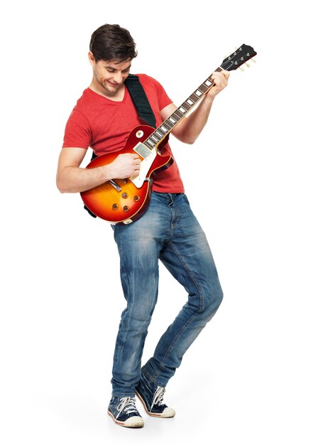 Junger Gitarrist spielt auf der E-Gitarre mit hellen Gefühlen, isoliert auf weißer Wand