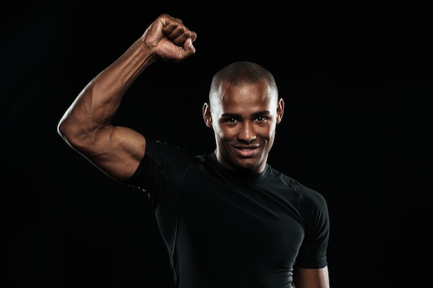 Junger glücklicher afroamerikanischer Sportmann, der seinen Sieg mit erhobenem Arm feiert
