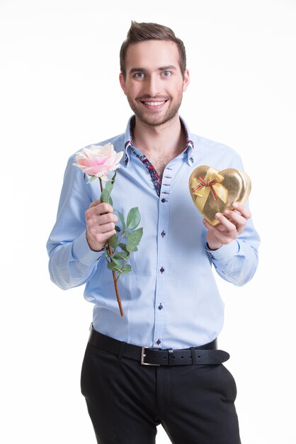 Junger glücklicher Mann mit einer rosa Rose und einem Geschenk - lokalisiert auf Weiß.