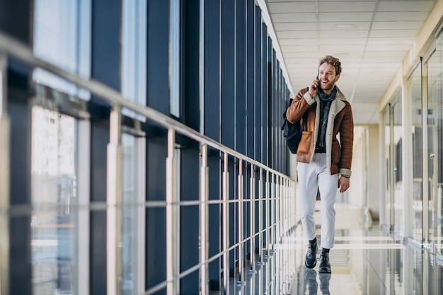 Junger gutaussehender Mann am Flughafen sprechend am Telefon