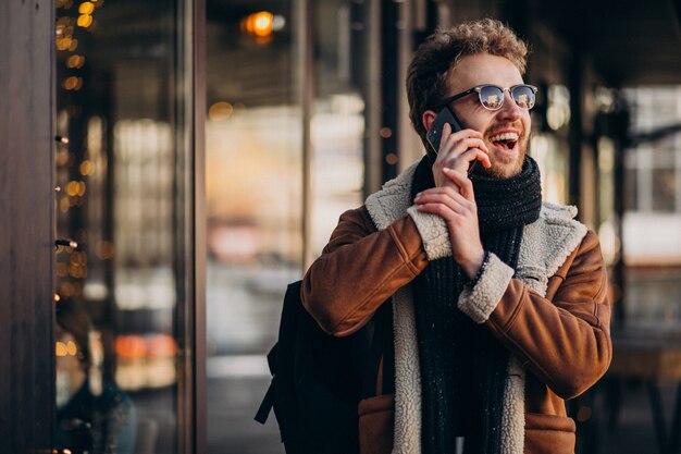 Junger gutaussehender Mann, der am Telefon durch den Flughafen spricht