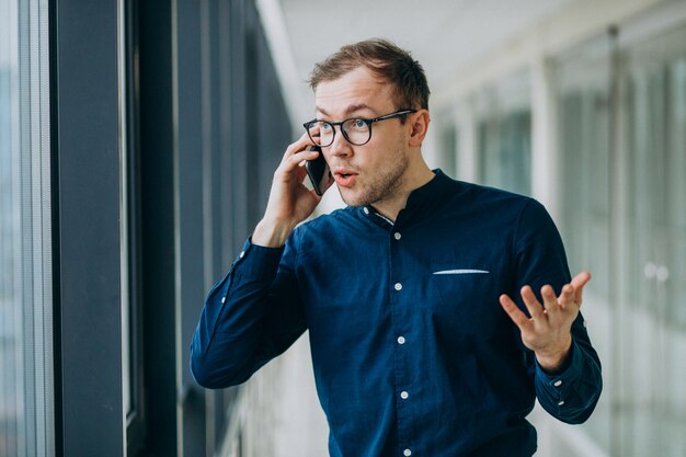 Junger gutaussehender Mann, der am Telefon im Büro spricht