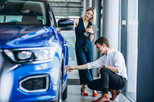 Junger gutaussehender Mann, der ein Auto in einem Autosalon wählt