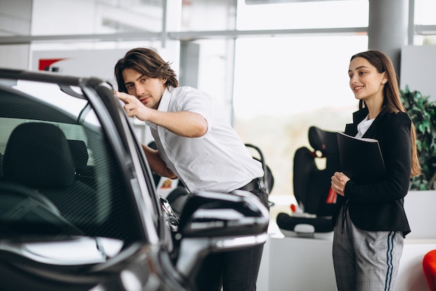 Junger gutaussehender Mann, der ein Auto in einem Autosalon wählt