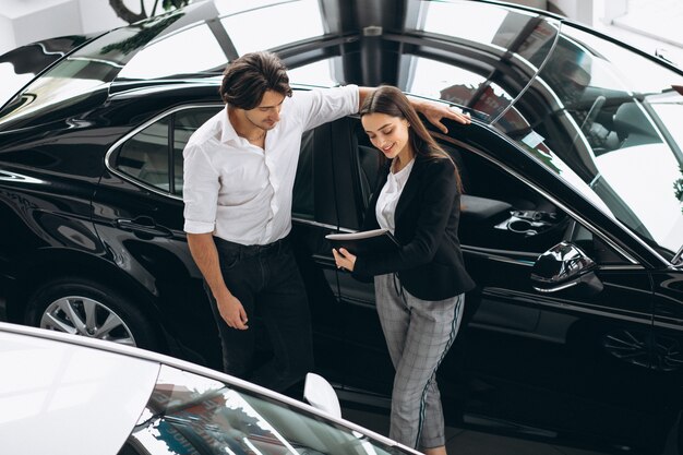 Junger gutaussehender Mann, der ein Auto in einem Autosalon wählt