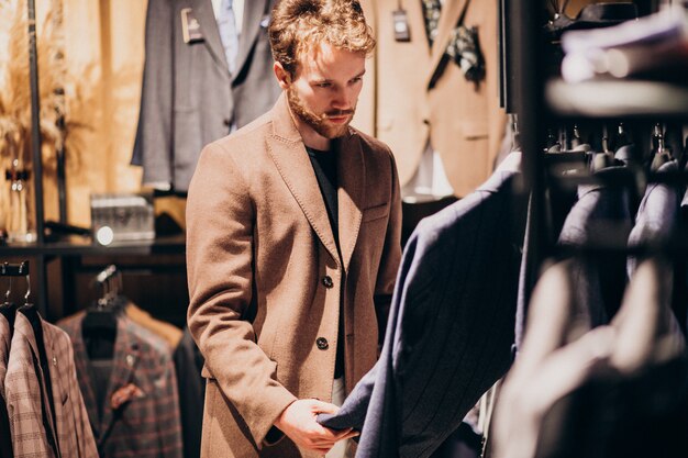 Junger gutaussehender Mann, der Kleidung am Shop wählt