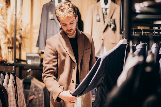 Junger gutaussehender Mann, der Kleidung am Shop wählt