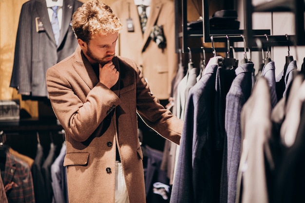 Junger gutaussehender Mann, der Kleidung am Shop wählt