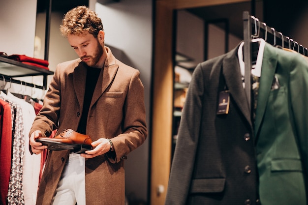 Junger gutaussehender Mann, der Schuhe an einem Shop wählt