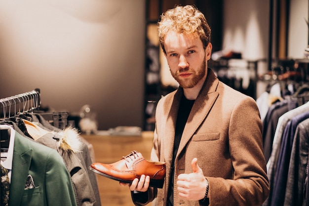 Kostenloses Foto junger gutaussehender mann, der schuhe an einem shop wählt